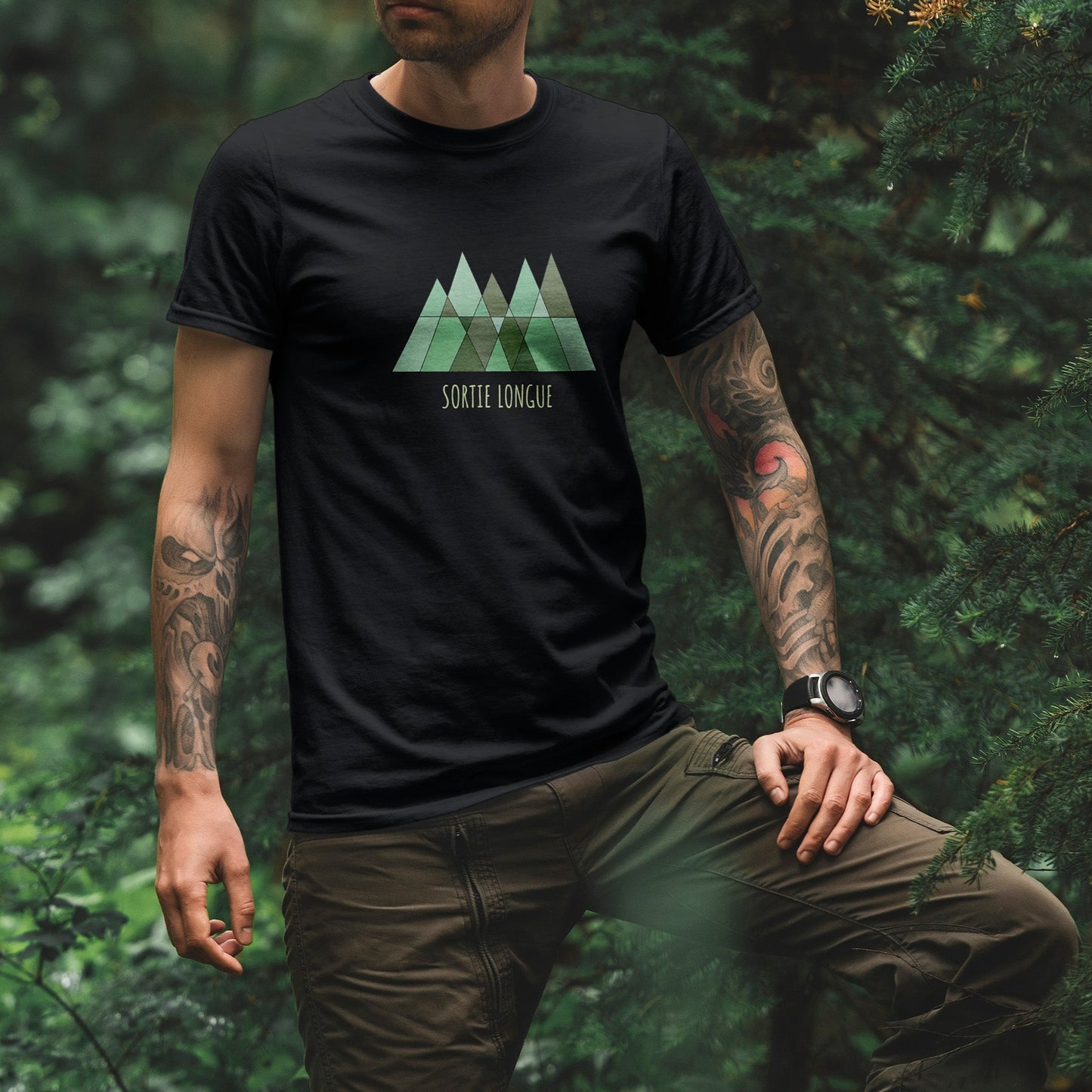 T-shirt unisexe Sortie Longue noir porté en forêt, vue de face, logo triangles verts imprimé avec texte Sortie Longue, tenue outdoor minimaliste pour sentier, marche et sorties dehors.