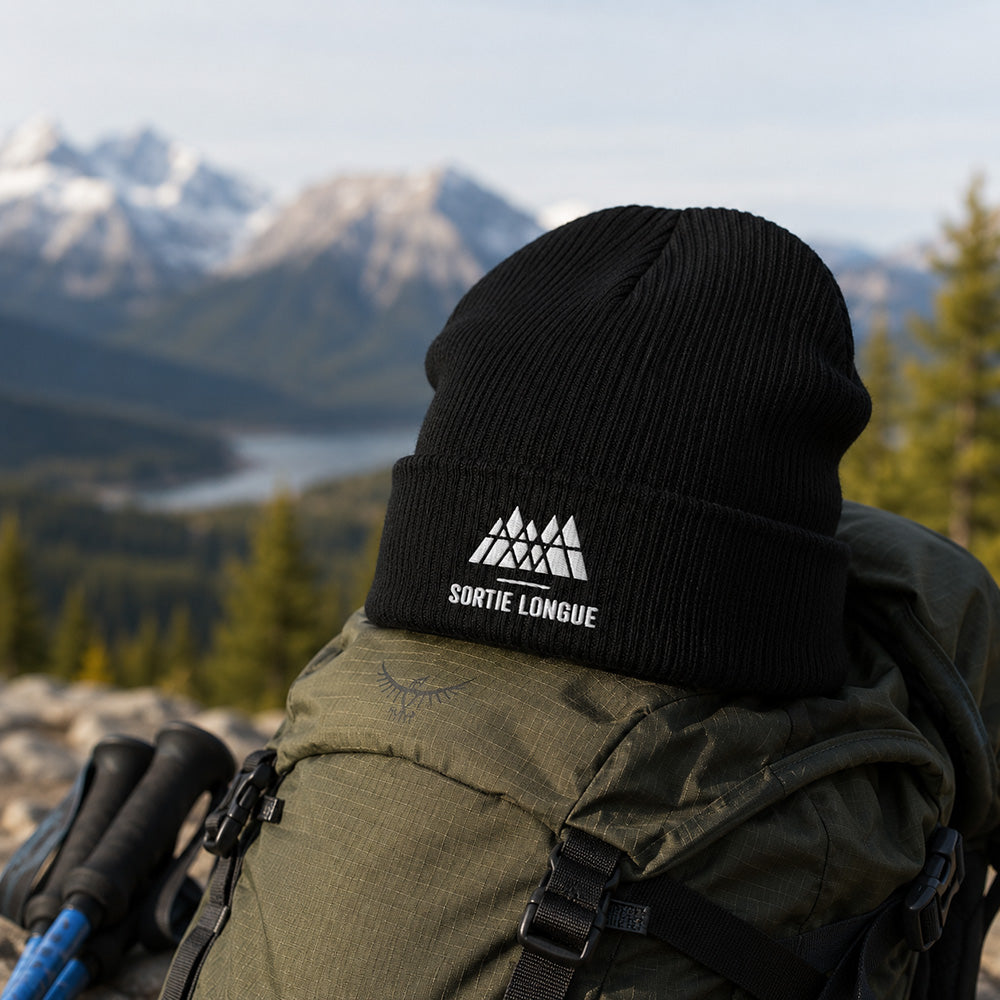 Bonnet tricoté coton bio logo Sortie Longue posé sur un équipement de randonnée en montagne