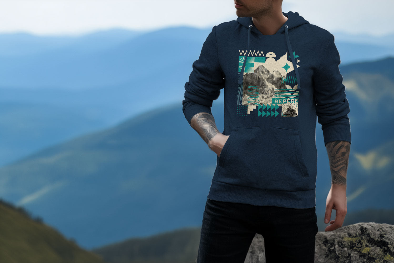 Homme portant un sweat à capuche en extérieur, face à un paysage de montagne.
