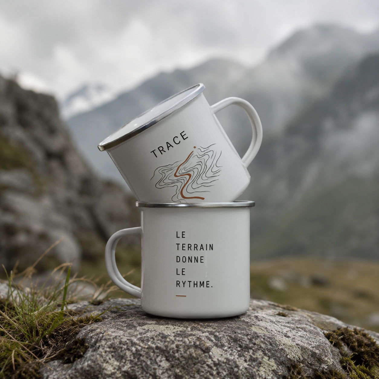 Deux mugs métal émaillé Sortie Longue avec visuels outdoor Trace et Le terrain donne le rythme, inspirés de la montagne, du trail, de la randonnée et des moments dehors.