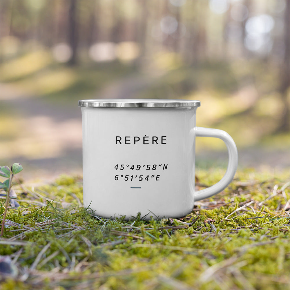Mug émaillé Repère posé dehors sur la mousse, avec design minimaliste inspiré des repères de terrain et de l’orientation.