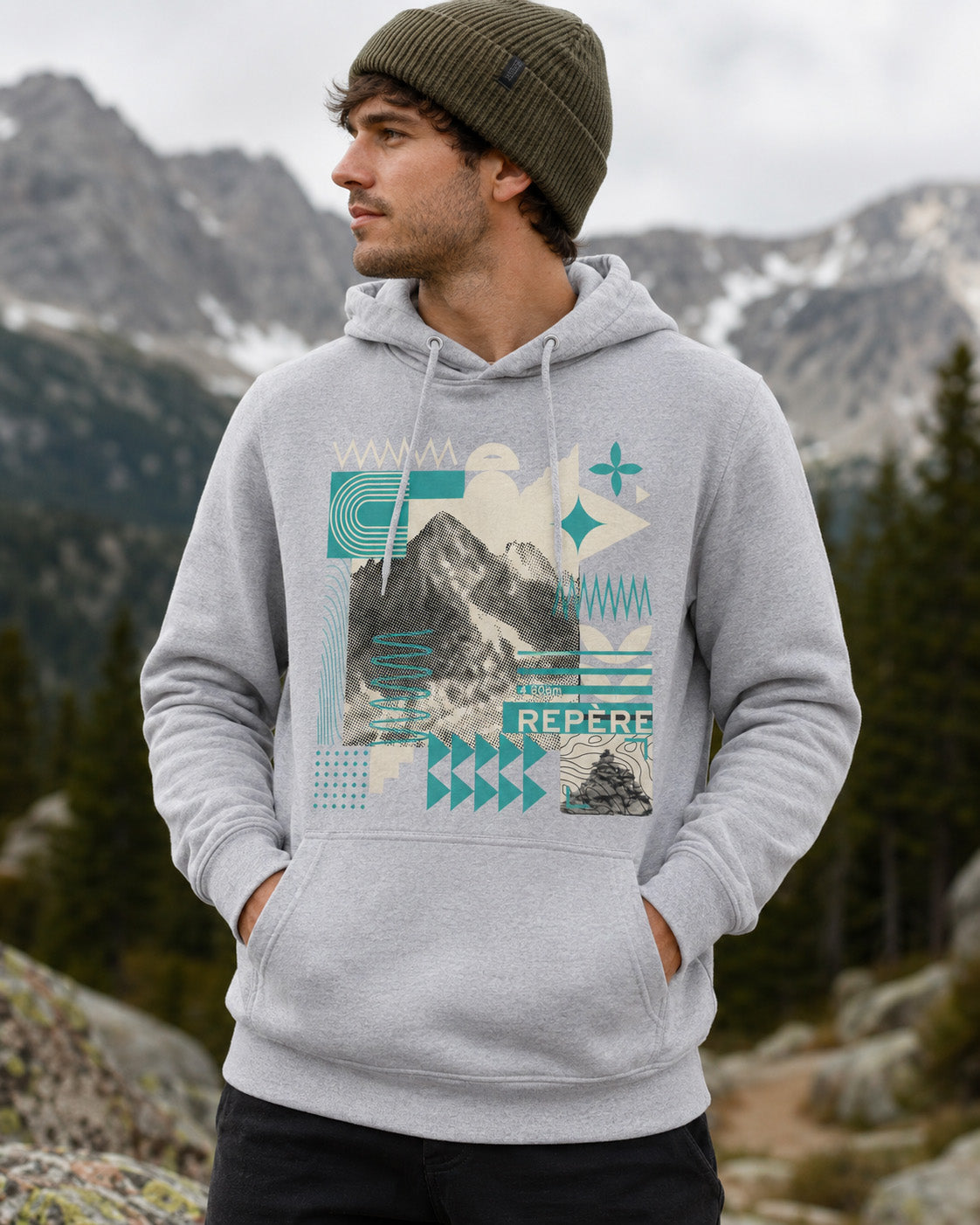Sweat à capuche unisexe Repère Sortie Longue gris porté par un homme en extérieur avec vue sur les montagnes