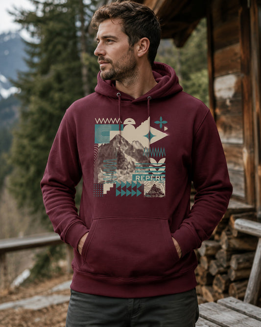 Sweat à capuche unisexe Repère Sortie Longue bordeaux porté par un homme devant un chalet en montagne