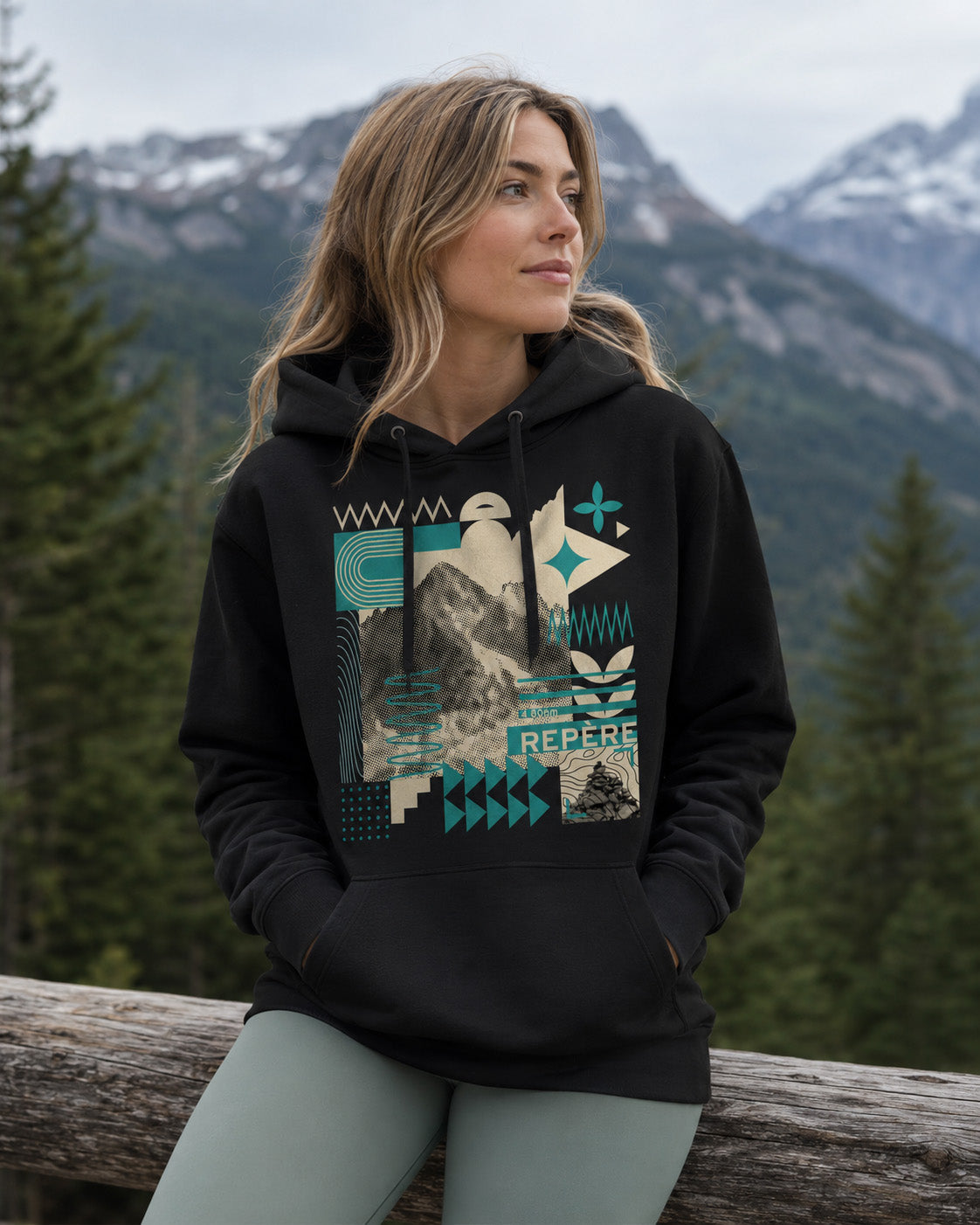 Sweat à capuche unisexe Repère Sortie Longue noir porté par une femme assise en extérieur dans un paysage alpin