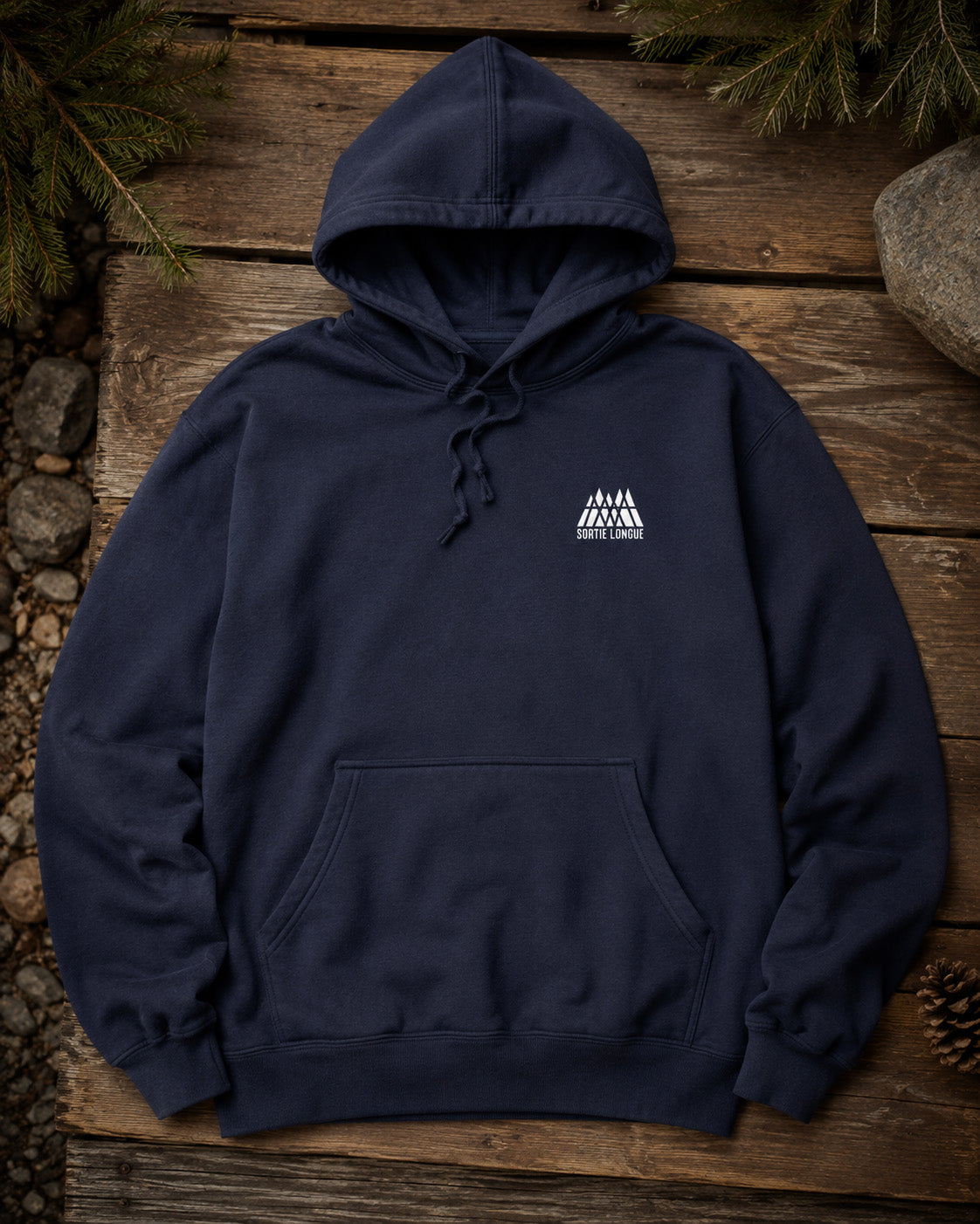 Sweat à capuche bleu marine Sortie Longue posé sur du bois avec logo blanc sur la poitrine