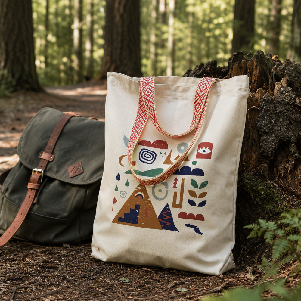 Tote bag coton recyclé Nature & Dénivelé Sortie Longue posé en forêt près d’un sac à dos