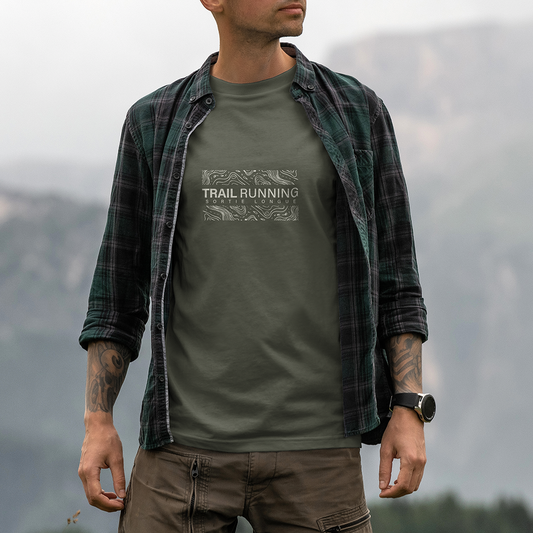 Modèle portant le t-shirt Sortie Longue vert kaki en extérieur, vue de face, design « Trail Running » avec fragments de carte topo et courbes de niveau, impression centrée; t-shirt unisexe cartographie.