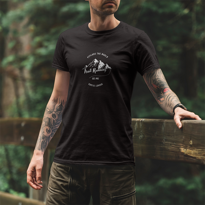 Modèle portant le t-shirt Sortie Longue noir en extérieur, vue de face, design « Explore the world » et « Trail running » avec chaîne de montagnes stylisée; tenue pour marche, sentier et déplacements.