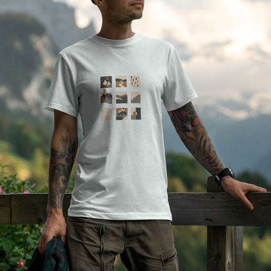 T-shirt unisexe blanc Sortie Longue porté en extérieur, motif central en grille de pictogrammes inspirés du terrain (relief, lignes, météo). Photo lifestyle avec paysage de montagne.