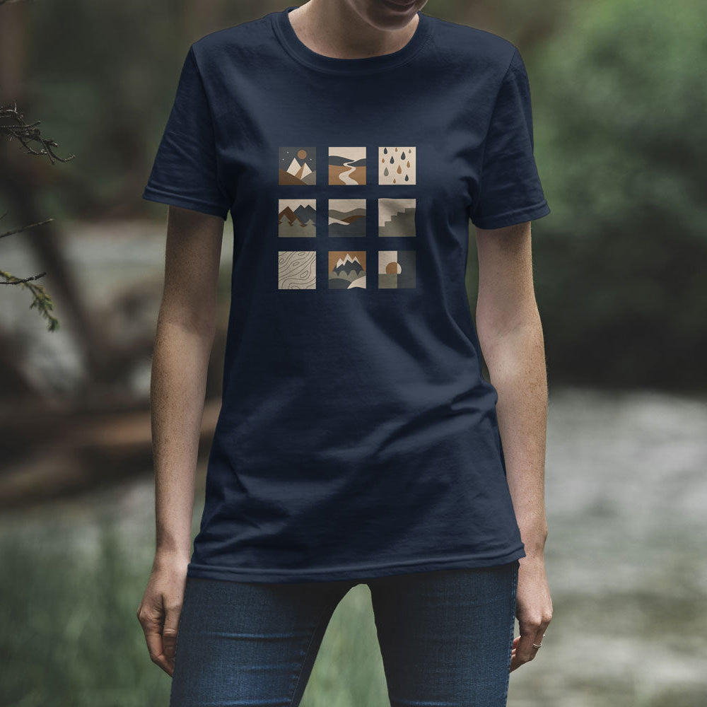 T-shirt unisexe bleu marine Sortie Longue porté en extérieur, motif graphique en grille de pictogrammes paysage sur la poitrine. Photo lifestyle, tenue sobre inspirée du dehors.