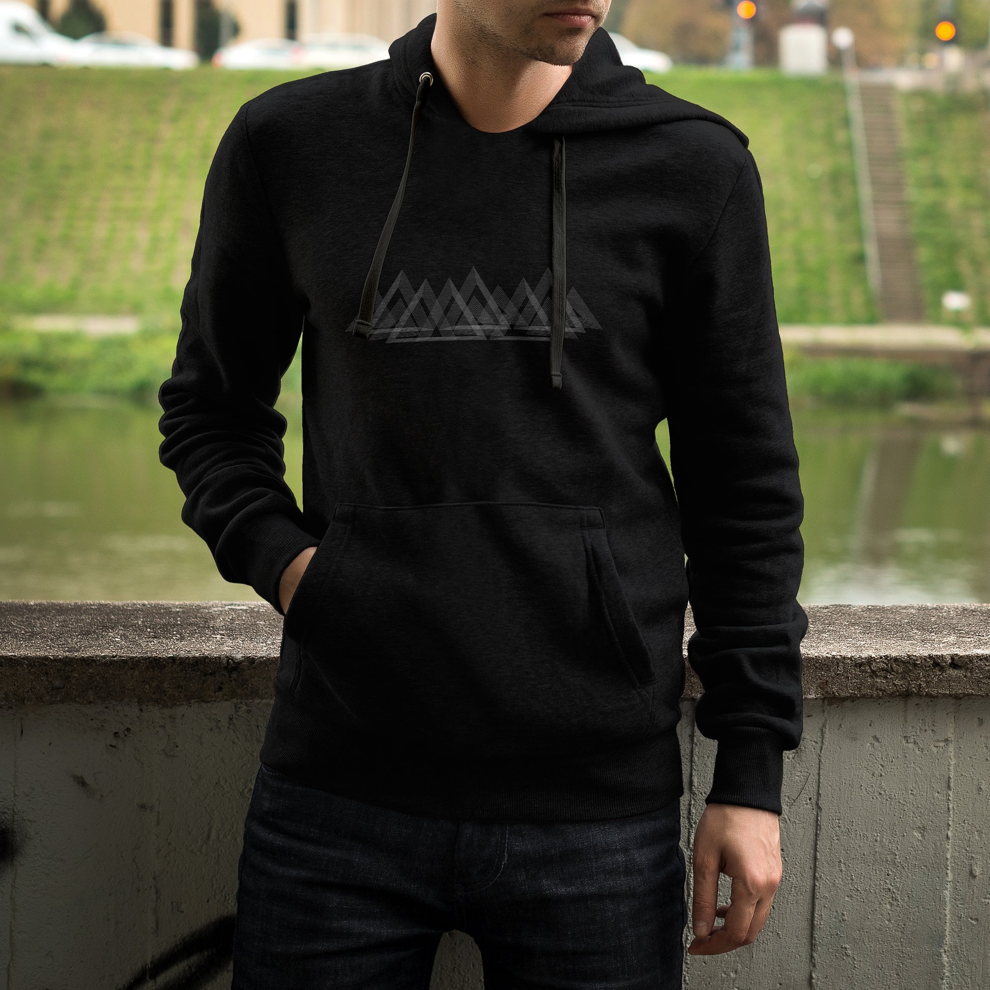 Sweat à capuche unisexe noir Sortie Longue porté en extérieur, vue de face, motif montagnes en lignes fines visible sur la poitrine, hoodie outdoor lié aux approches, pauses et fins de journée au frais.