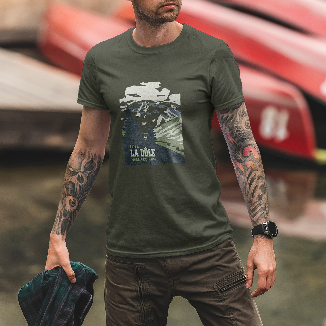 T-shirt unisexe Sortie Longue kaki porté en extérieur, vue de face, design La Dôle imprimé au centre, sommet du Jura en style affiche, tenue sobre pour marche, randonnée et sorties dehors.