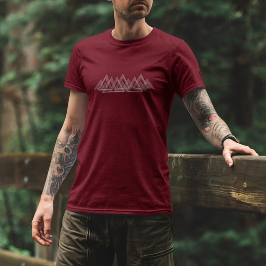 Modèle portant le t-shirt Sortie Longue bordeaux, vue de face en extérieur, ligne de montagnes minimalistes imprimée en traits fins, silhouette de crête discrète; tenue pour marche, sentier et sorties dehors.